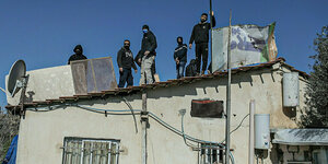 Vermummte Männer stehen auf einem Dach