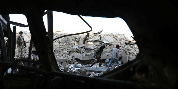 Männer stehen in den Trümmern eines zerbombten Hauses