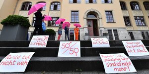 Frauen mit rosa Regenschirmen und Schildern: "50/50" und " Pariteé tur nicht weh"