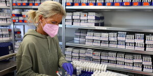 Eine Laborantin sortiert Fläschchen mit Coroa-Proben