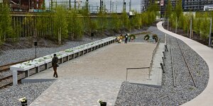 Zwei Besucher laufen an den Gedenktafeln des Gedenkortes "denk.mal Hannoverscher Bahnhof" am Lohseplatz in der Hafencity entlang.