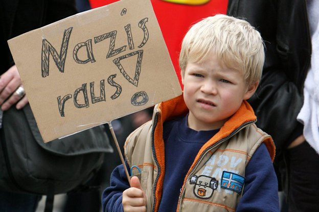 Kleines Kind mit Schild "Nazis raus" in der Hand