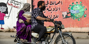 Ein Mann und eine Frau auf dem Moped vor geschlossenen Läden