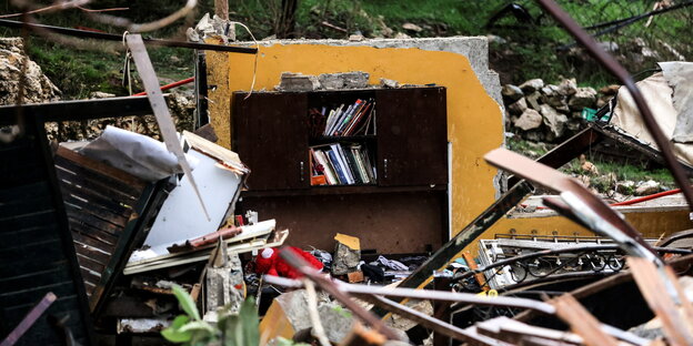 Ein Bücherregal steht in den Trümmern des Hauses