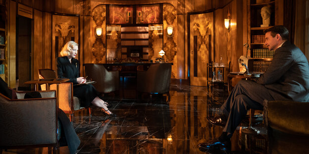Dr. Lilith Ritter (Cate Blanchett) und Stanton Carlisle (Bradley Cooper) sitzen in einem Raum mit edler Art-Déco-Holztäfelung.