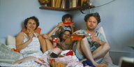 Eine Familie mit 2 Mädchen sitzt Melone essend fröhlich im Bett