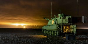 Ein angeleuchteter grüner Panzer der US Armee bei einer Gefechtgsübung