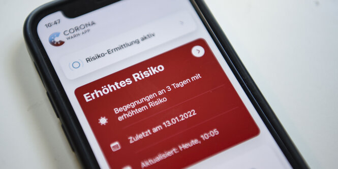 Smartphone mit Corona-Warnapp, die ein erhöhtes Risiko anzeigt