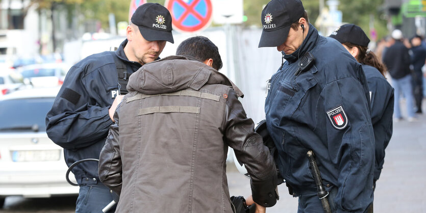 Ein Mann muss zwei Polizisten den Inhalt seines Rucksacks zeigen