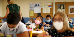 SchülerInnen sitzen mit Maske im Klassenzimmer