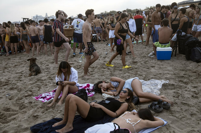 Am Strand liegen viele junge Menschen