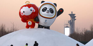 Zwei große Plastikfiguren, die eine mit einem Globuskopf und die andere ist ein Panda. Beide stehen auf einem Schneeberg.