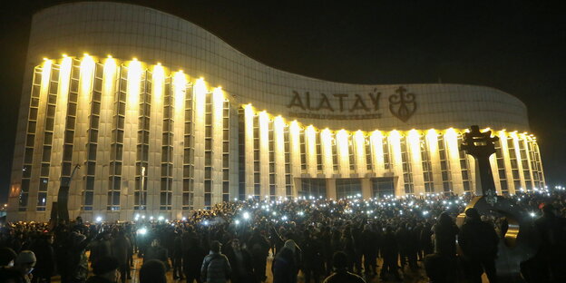 Protestierende erleuchte ihre Smartphones vor einem beleuchteten Gebäude