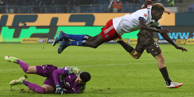 Der Fußballer BAkery Jatta von HSV fliegt über St. Paulis Torwart Nikola Vasilj