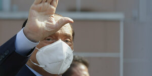 Silvio Berlusconi winkt und trägt eine weiße Maske