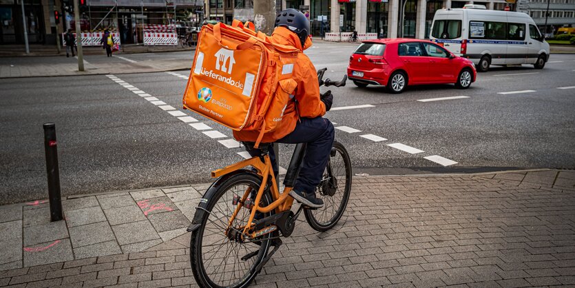 Ein Fahrradkurier fährt über den Bürgersteig hin zur Straße