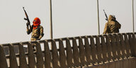Soldaten stehen auf einer Straßenbrücke.