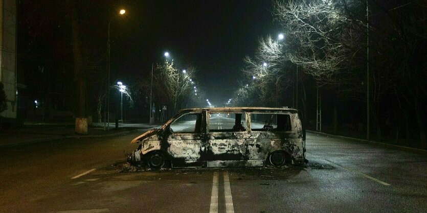 Ein verbrannter Polizeibus auf einer menschenleeren Straße