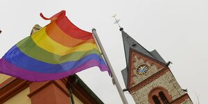 Eine regenbogenfahne vor einer katholischen Kirche