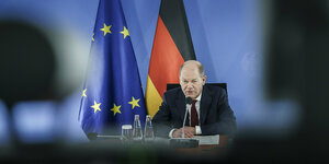 Bundeskanzler Olaf Scholz vor einer EU- und einer Deutschlandfahne