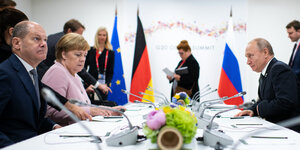 Olaf Scholz sitzt neben ANgela Merkel an einem Verhandlungstisch, Wladimir Putin sitzt ihnen gegenüber
