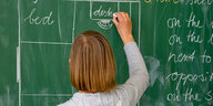 Eine Lehrerin schreibt englische Wörter an die grüne Schultafel