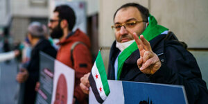 Ein syrischer Aktivist macht vor dem Gerichtsgebäude das ·Victory-Zeichen