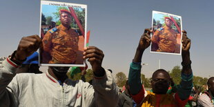 Zwei Männer hlaten Fotos des Militärchefs aus Burkina Faso in die Höhe