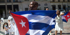 Ein Mann hält eine kubanische Flagge, während er an einem Protest auf der Plaza de la Constitution in Malaga zur Unterstützung der kubanischen Bevölkerung teilnimmt