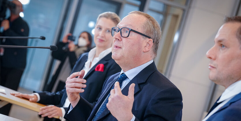 Max Otte steht zwischen den AfD-Abgeordneten Alice Weidel und Tino Chrupalla und spricht im Bundestag