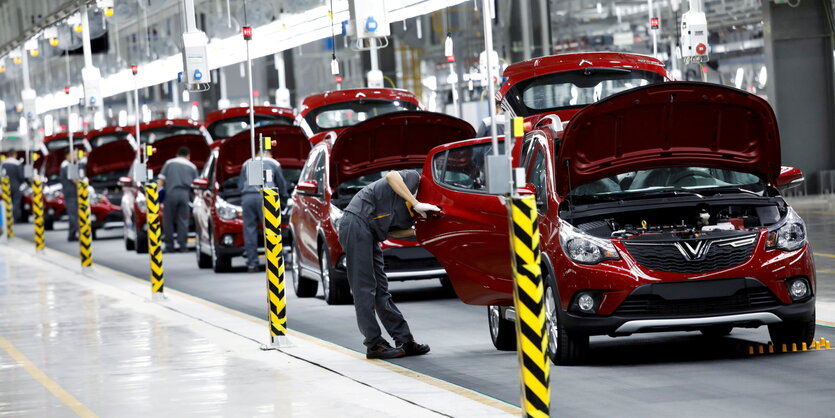 Fabrikhalle mit Fließband auf dem Arbeiter an Autos werkeln