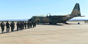 Soldaten marschieren auf dem Flugfeld zu einem Transporter