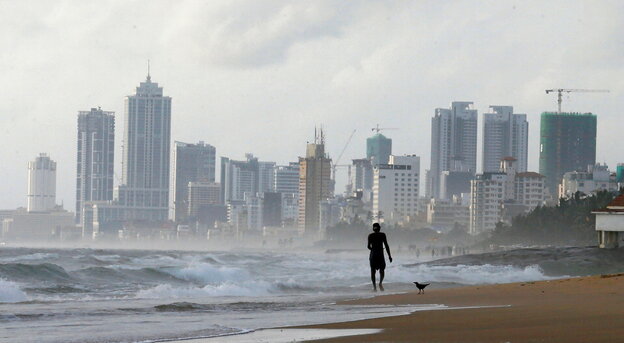 Skyline mit Hochhäusern in Colombo, ein Mann geht am Meer
