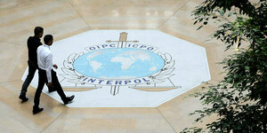 Interpol Logo auf einem Fußboden: eine Weltkarte, ein Schwert