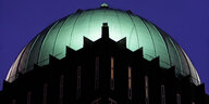 Die angeleuchtete grüne Kuppel des Anzeiger-Hochhauses in Hannover hebt sich gegen den tiefblauen Abendhimmel ab