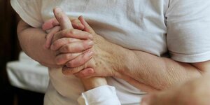 Ein Pfleger hält die Hand eines Pazienten