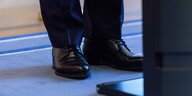 Bildauschnitt wo elegante Schuhe vor einem Rednerpult zu sehen sind