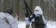 Zwei Männer in weißer Kampfmontur und mit Gewehr