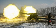 Eine Haubitze, zwei Feuerbälle und ein russischer Soldat in Winterlandschaft im Süden der Region Rostov während einer Übung
