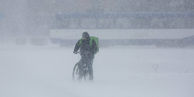Das Foto zeigt einen Radahrer im dichten Schneetreiben.