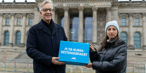 Eine Frau und eine Mann halten ein Schild mit der Aufschrift "Peta-Klima-Rettungspaket"