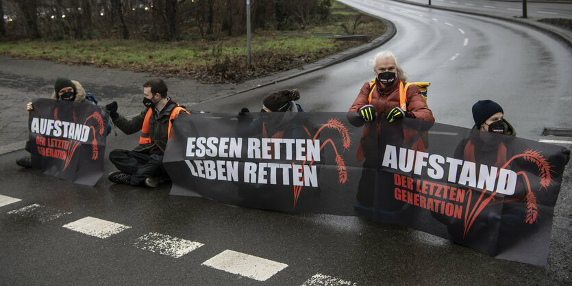 Menschen sitzen mit Transparenten auf der Straße