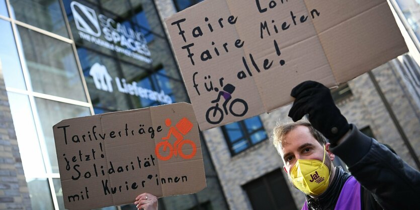 Ein Mann hält ein Schild mit Forderungen nach besserer Bezahlung hoch