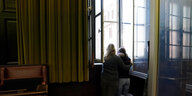 Zwei Frauen stehen im Gerichtssaal am Fenster und gucken raus