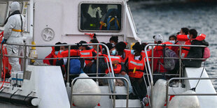 Eine gruppe Menschen mit roten Schwimmwesten auf einem Boot