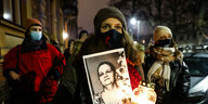 Frauen mid Mundschutz und Kerzen wie einem Totenbild in der Hand demonstrieren in warschau