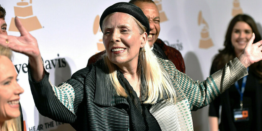 Joni Mitchell hebt beide Arme in die Höhe