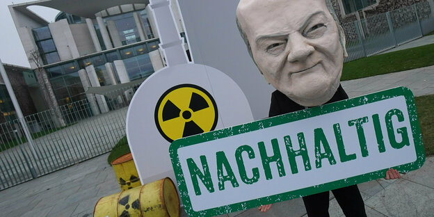 Demonstrant mit Scholz-Maske und Fässern mit Atombymbolen vor dem Kanzleramt