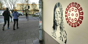 Ein Graffiti zeigt eine Frau mit Mundschutz und das Coronavirus an einer Haeuserwand