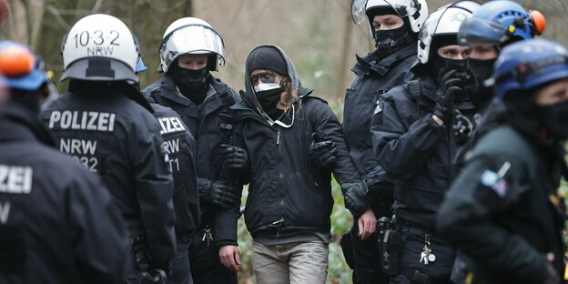 Schwarz gekleidete Polizisten führen einen Aktivisten in ihrer Mitte ab
